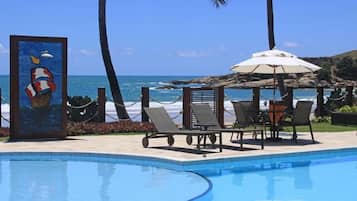 Una piscina al aire libre, sombrillas, sillones reclinables de piscina