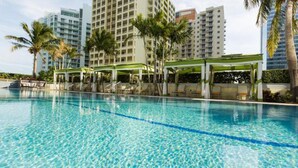 A swimming pool with clear blue water, surrounded by palm trees and modern buildings. - 1 Bedroom Brickell Condo (Miami)
