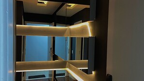 A modern interior with a wooden floor, a glass partition, and a ceiling with recessed lighting.