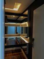 Un intérieur moderne avec un plancher en bois, une cloison en verre et un plafond doté d’un éclairage encastré.