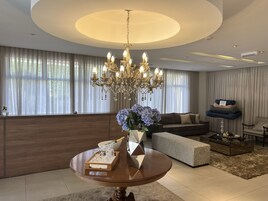 Un salon moderne avec un lustre, une table ronde ornée d’un vase de fleurs, un canapé et une table basse.
