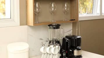 Uma cozinha com uma estante de madeira para vinhos, com vários copos de vinho, uma cafeteira e um recipiente branco.