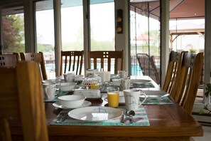 A dining table set for breakfast with chairs, plates, cups, and a glass of orange juice. - Shane Acres Country Inn (Juneau)