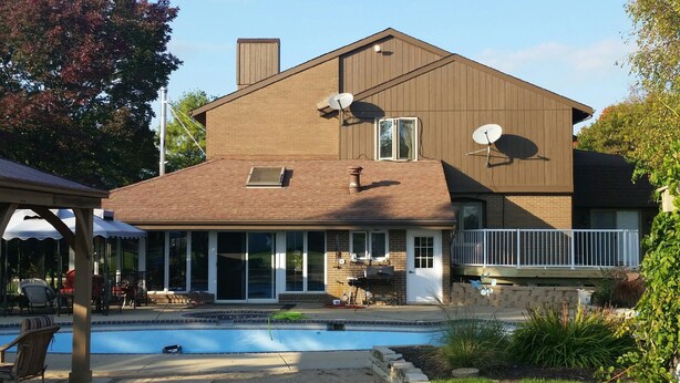 A two-story house with a swimming pool, satellite dishes, and a covered patio area.
