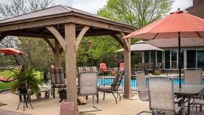 A covered outdoor area with a pool, lounge chairs, and umbrellas. - Shane Acres Country Inn (Juneau)