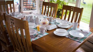 A dining table set with plates, cups, and a pitcher, surrounded by wooden chairs.