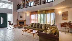 A spacious living room with a green sofa, a wooden coffee table, a rocking chair, and a fireplace. - Halepa Hill (Rethymno)