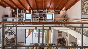A spacious loft with a wooden ceiling, a balcony with a railing, and a view of the outdoor patio area. - Halepa Hill (Rethymno)