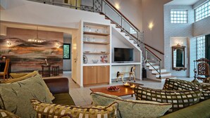 A spacious living area with a staircase, a television, and a painting on the wall. - Halepa Hill (Rethymno)