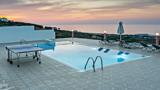 A rooftop pool with a table tennis table, lounge chairs, and a view of the sea at sunset. - Halepa Hill (Rethymno)