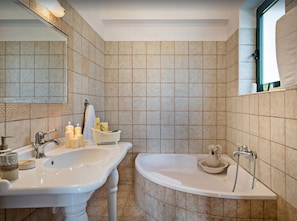 A bathroom with two sinks, a bathtub, and a mirror.