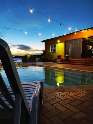 Una piscina al aire libre, sillones reclinables de piscina