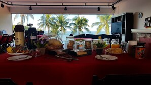 Une table dressée pour le petit-déjeuner avec vue sur les palmiers et la mer.