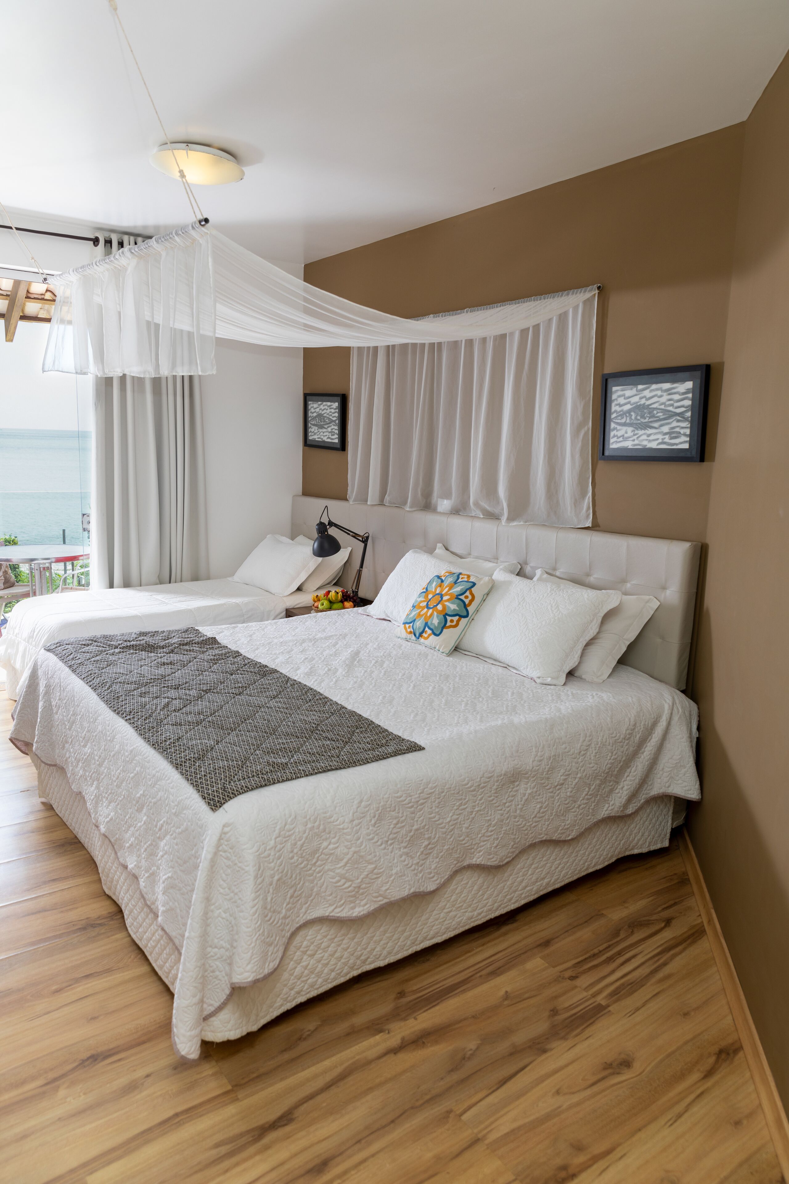 A bedroom with a large bed, a bedside lamp, and a view of the sea.