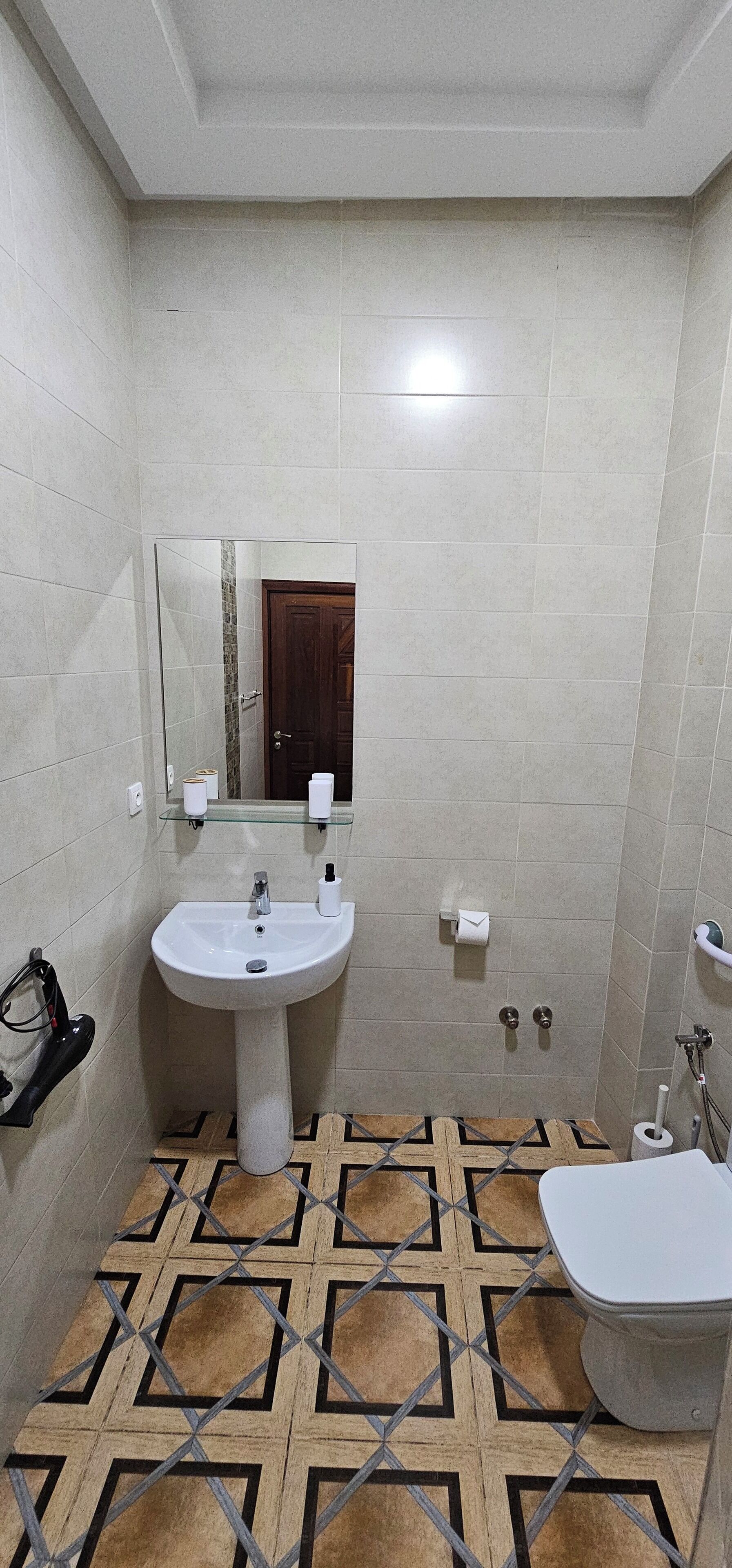 A bathroom with a white sink, a mirror, a toilet, and a shower area.