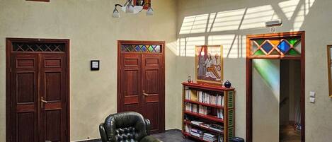 A spacious room with a high ceiling, a skylight, leather sofas, a small table, and a bookshelf.