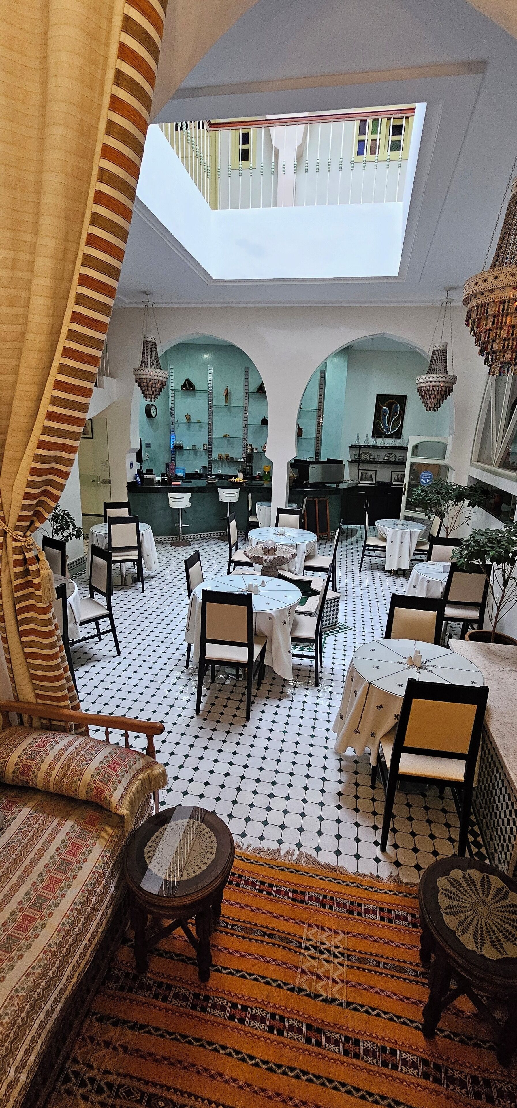 Un vaste espace dédié à la salle à manger, avec de nombreuses tables et chaises, un coin bar et une vue sur le ciel par une fenêtre en arc de cercle.