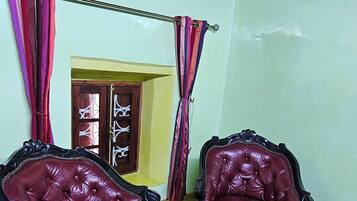 Une pièce comprenant deux fauteuils en cuir rouge, une table avec un plateau en verre, un tapis à motifs et un plancher en bois.
