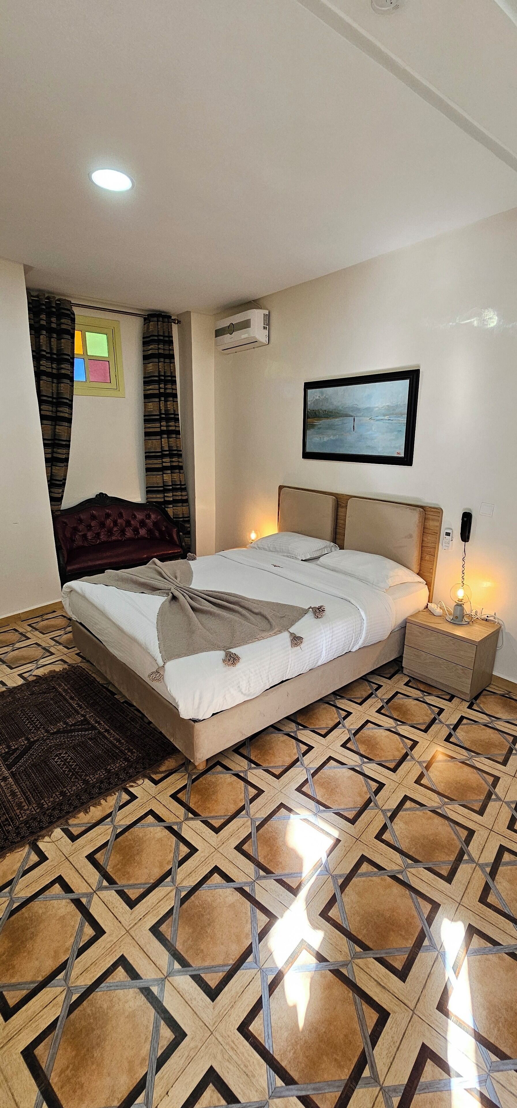 A bedroom with a bed, bedside table, and a wall-mounted air conditioner.
