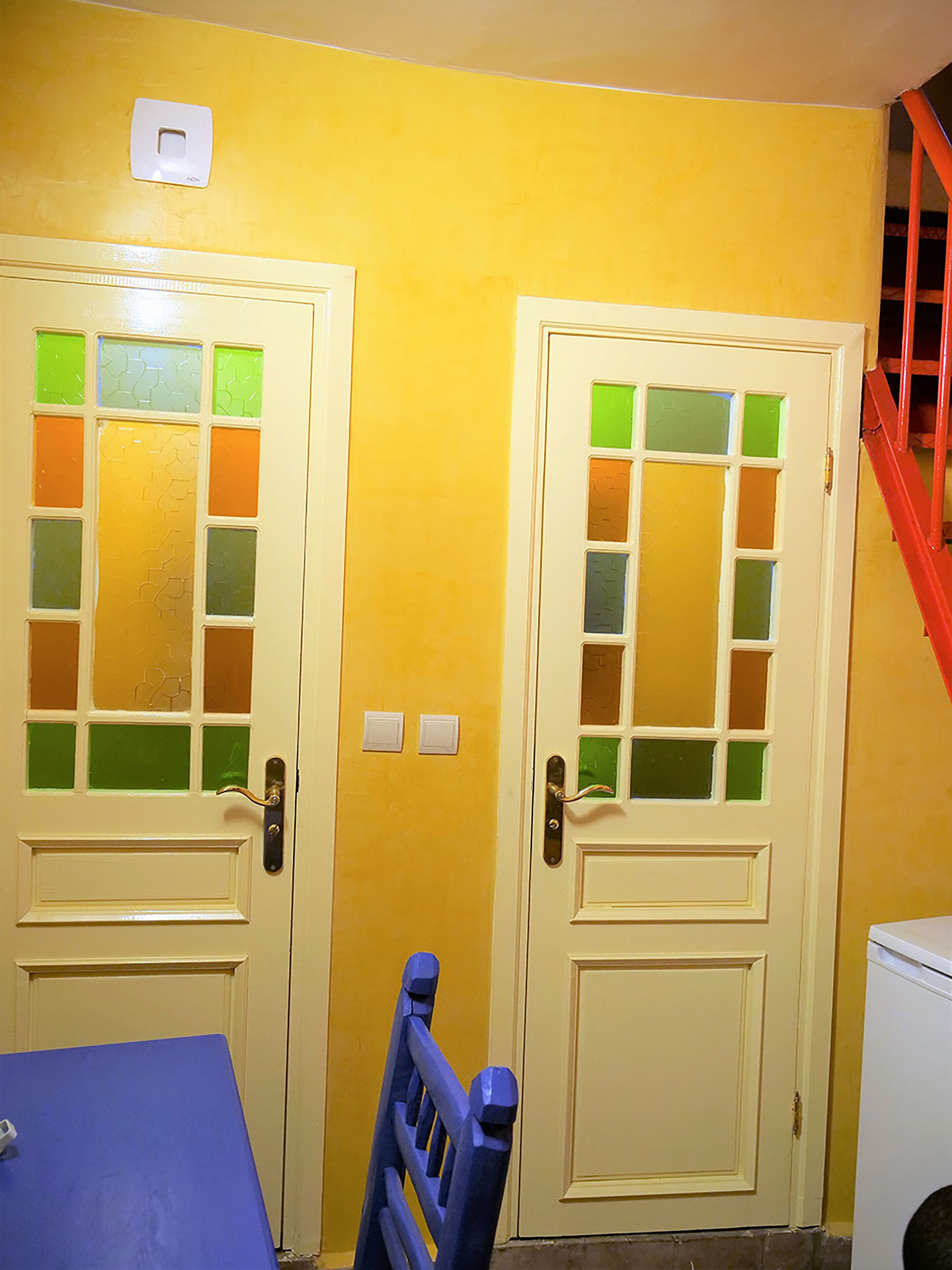 Two doors with frosted glass panels, a blue table, and a red staircase.