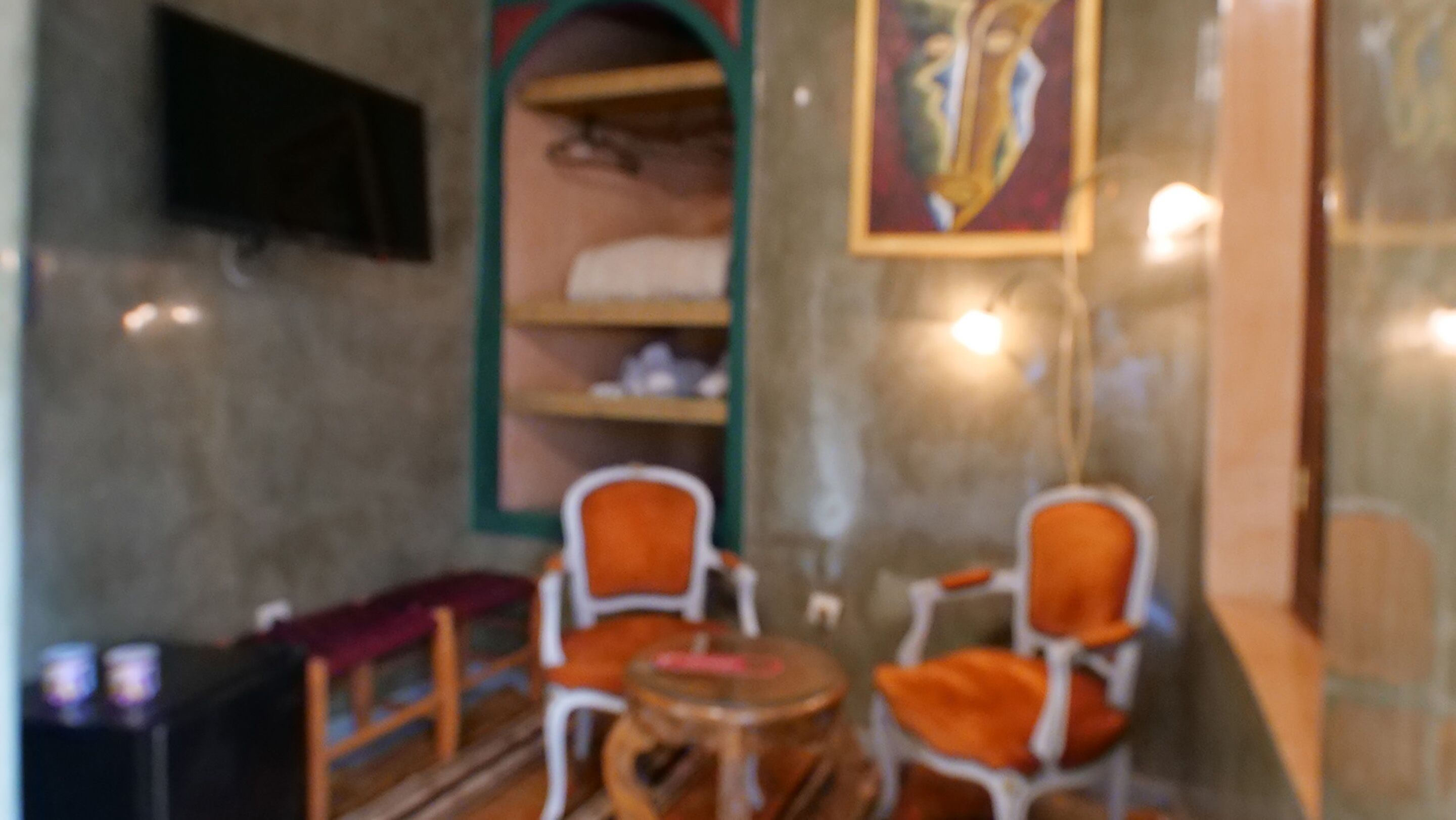 Una habitación con dos sillones naranjas y una mesa redonda pequeña.