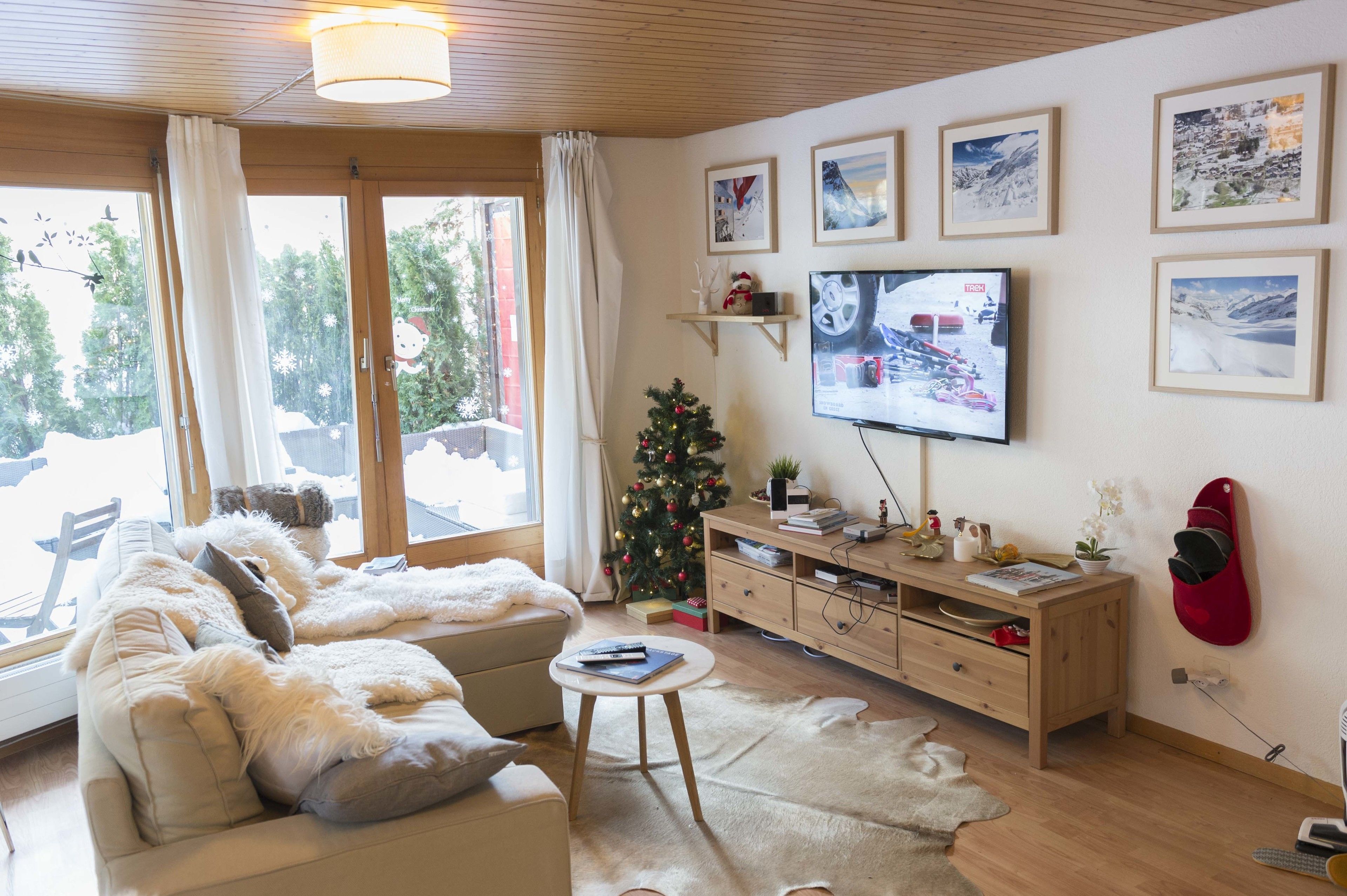 Un salon chaleureux avec un canapé, une table basse, un téléviseur et un sapin de Noël.