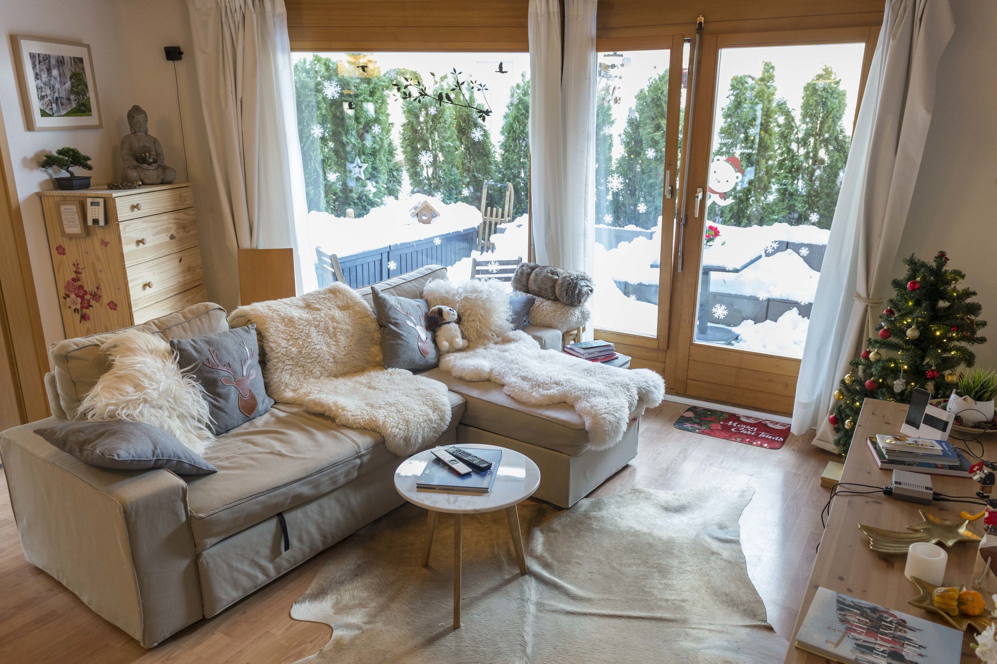 A cozy living room with a sofa, a coffee table, and a Christmas tree.