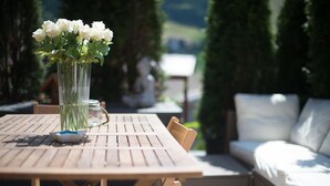 Une table en bois sur laquelle se trouvent un vase de fleurs blanches, un bocal en verre et un bol.