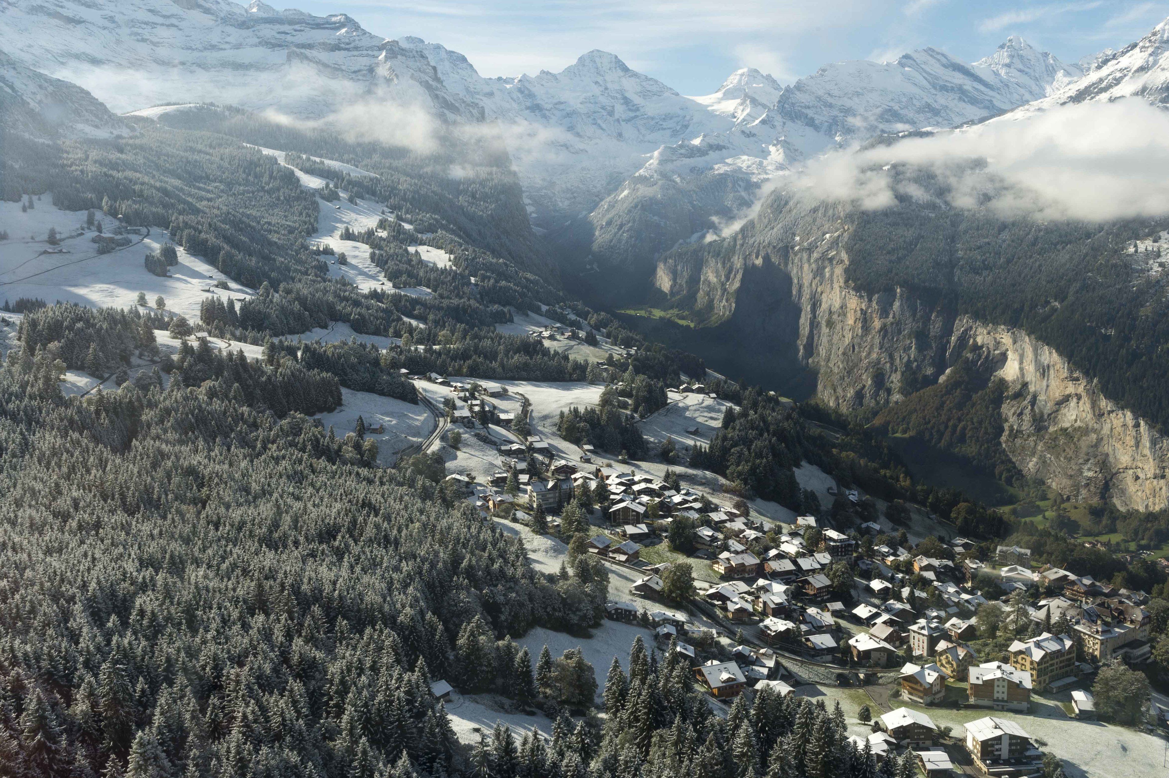 Un pueblo montañoso cubierto de nieve con edificios tradicionales y vistas al valle.