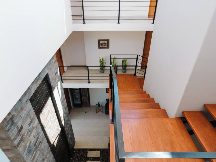 Un interior moderno con una escalera de madera, un entrepiso y una pared de piedra.