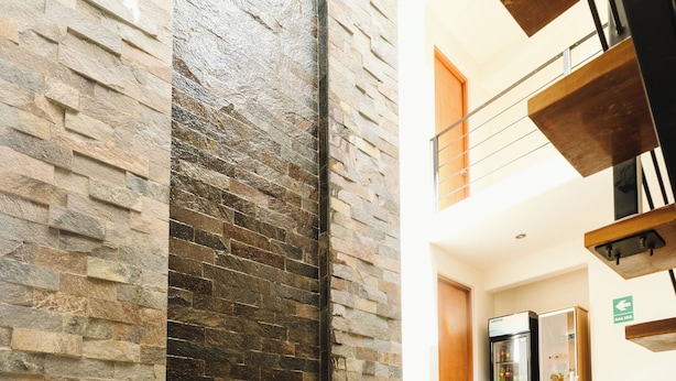 A modern interior with a stone wall, a glass water feature, and a refrigerator in the background. - Villa oasis (Ica)