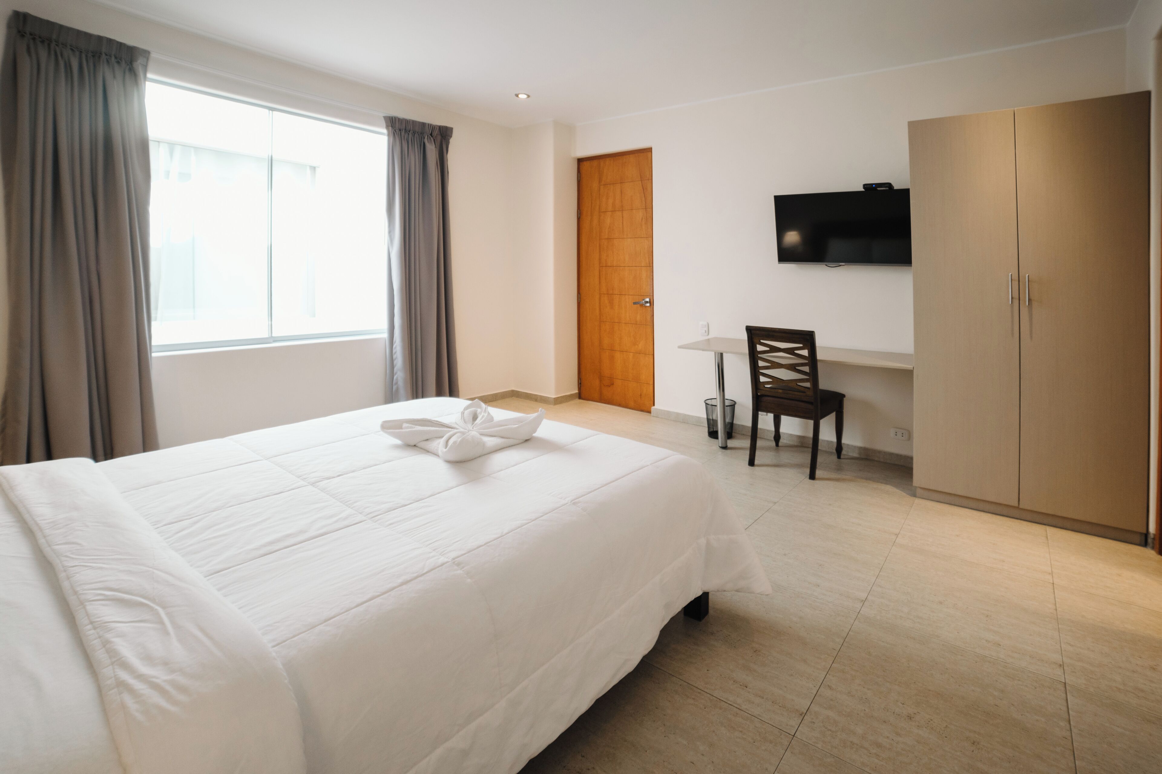 Ein Hotelzimmer mit einem großen Bett, einem Schreibtisch, einem Stuhl und einem Kleiderschrank.