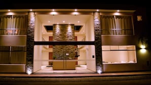 A modern building with a central atrium, stone facade, and multiple windows. - Villa oasis (Ica)