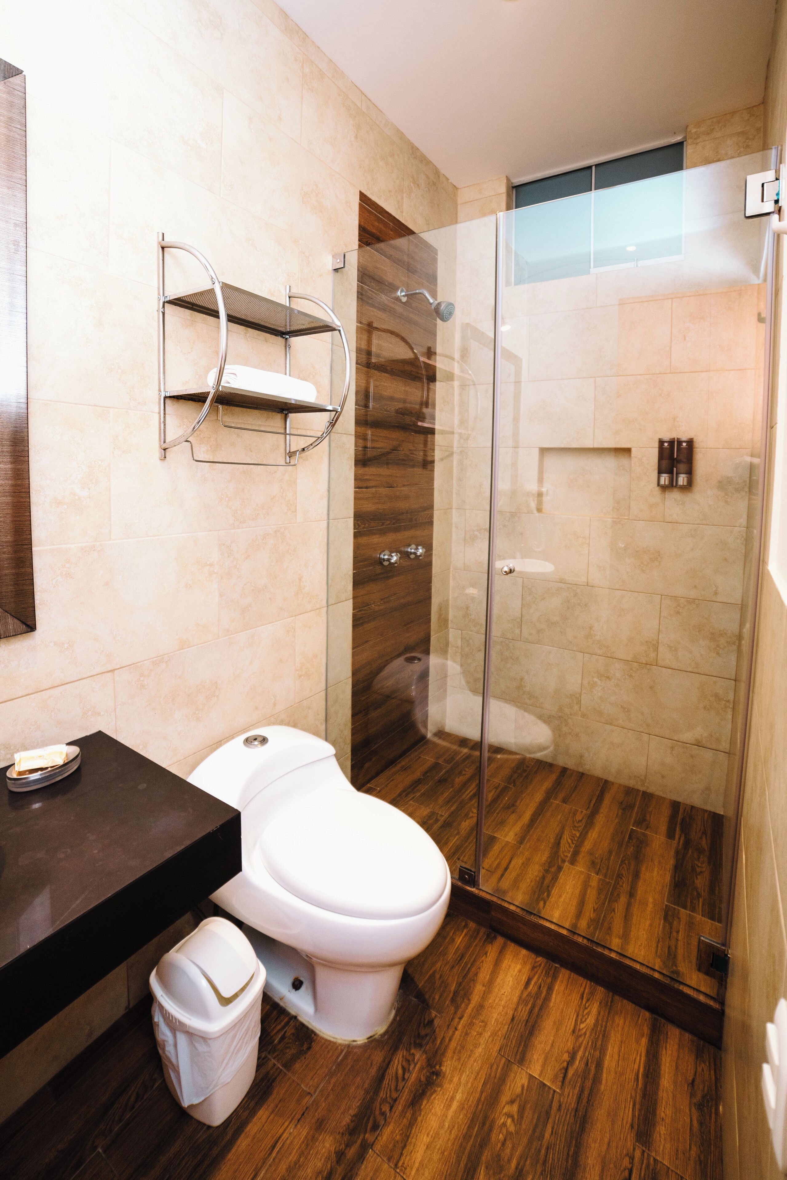 A modern bathroom with a glass-enclosed shower, a white toilet, and a dark wooden vanity.