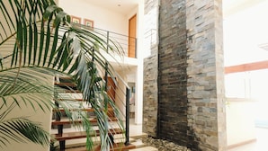 A modern interior with a staircase, stone wall, and indoor plants. - Villa oasis (Ica)