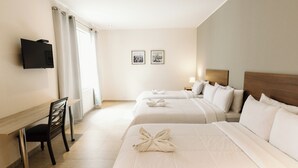 A hotel room with two beds, a desk, a chair, a flat-screen TV, and two framed pictures on the wall. - Villa oasis (Ica)