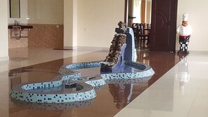 Een ontvangsthal met een decoratieve waterpartij, een klok aan de muur en een standbeeld van een kok.