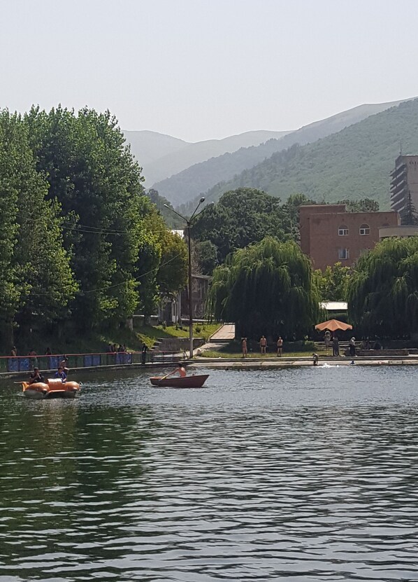 A calm lake with boats, a bridge, and buildings in the background.