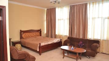 A bedroom with a bed, a sofa, a small table, and a nightstand.