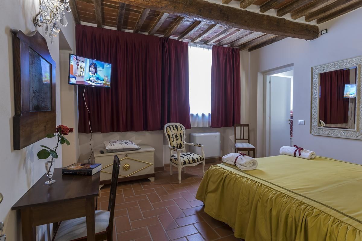 A room with a bed, a desk, a chair, a television, and a window with curtains.