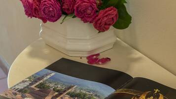 A white vase with pink roses on a white table.