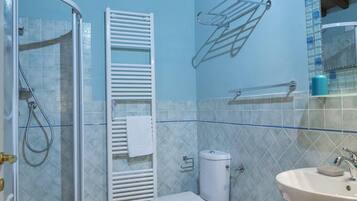A bathroom with a shower, toilet, bidet, and sink.