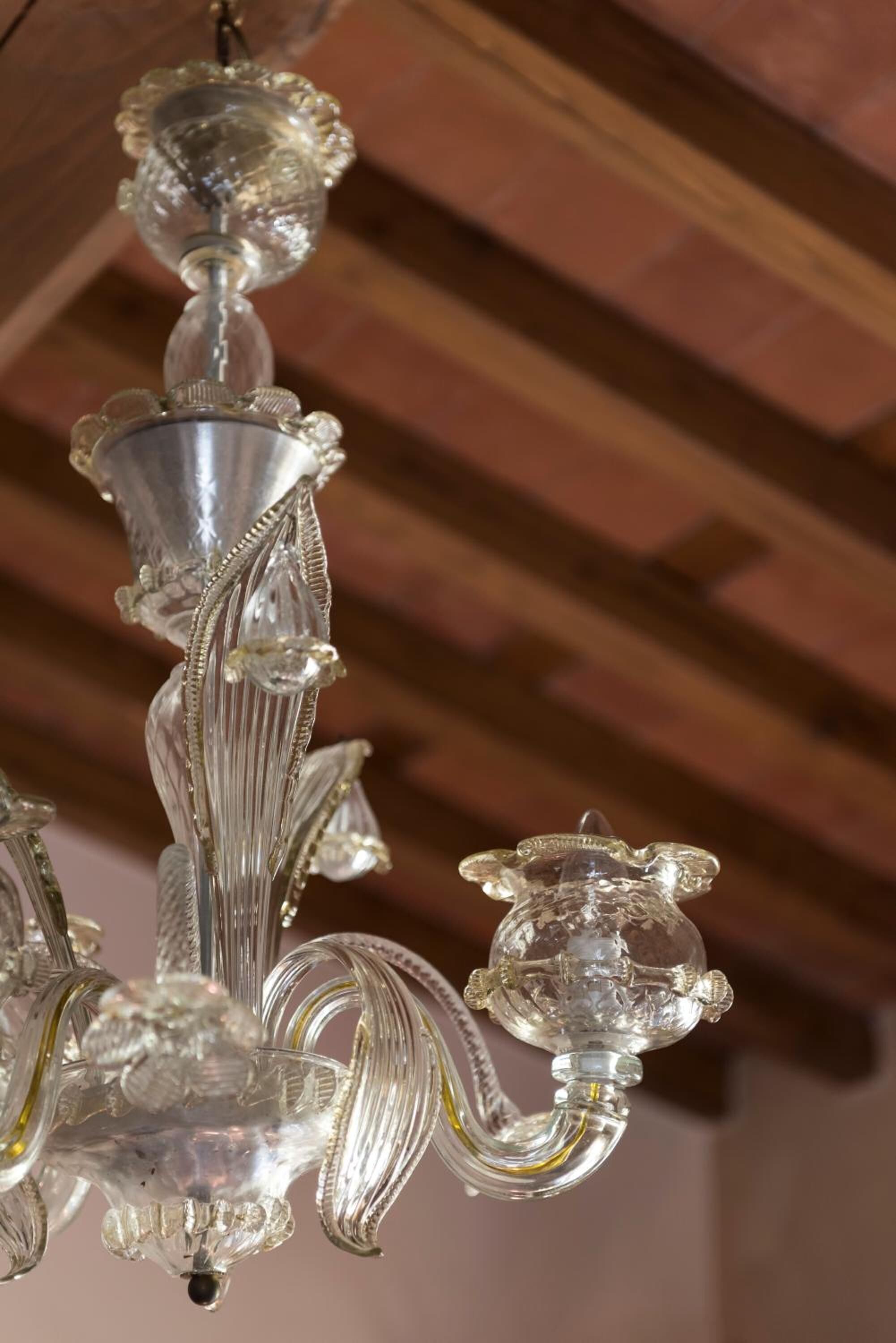 A chandelier with multiple crystal elements and a wooden ceiling.