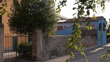 A street with a stone wall, a metal fence, and a building with a blue facade.