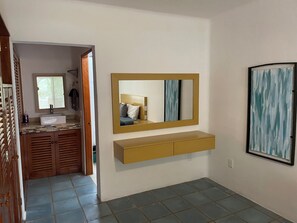 Un baño con lavamanos, espejo y toallero.
