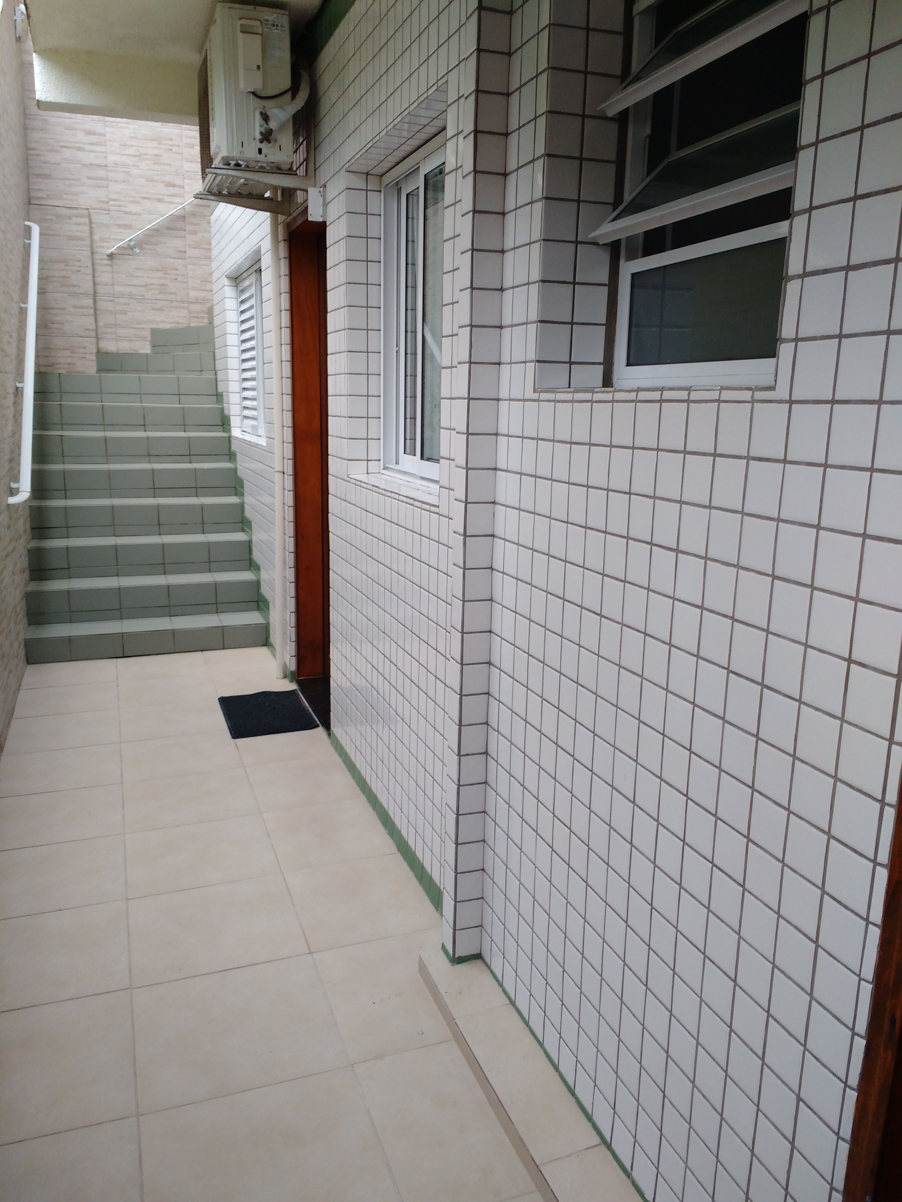 Ein schmaler Korridor mit gefliesten Wänden und einem gefliesten Boden, der zu einer Treppe führt.
