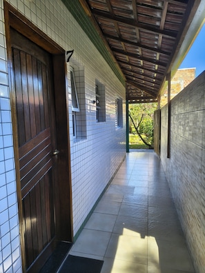 A corridor with tiled walls, a wooden door, and a tiled floor.
