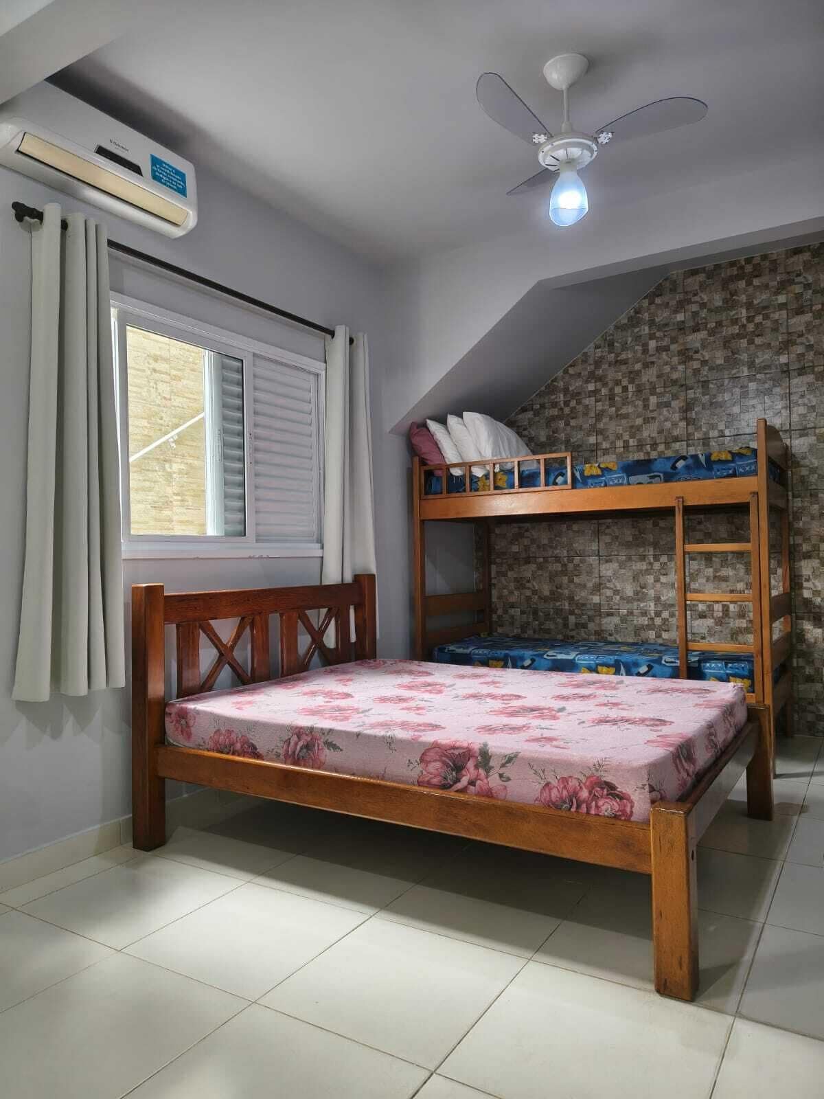 Un dormitorio con una litera, una cama individual, un ventilador de techo y un aire acondicionado.