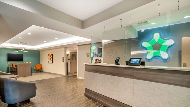 A modern reception area with a counter, seating, and a large screen. - Extended Stay America Premier Suites Greenville Woodruff Rd (Greenville)