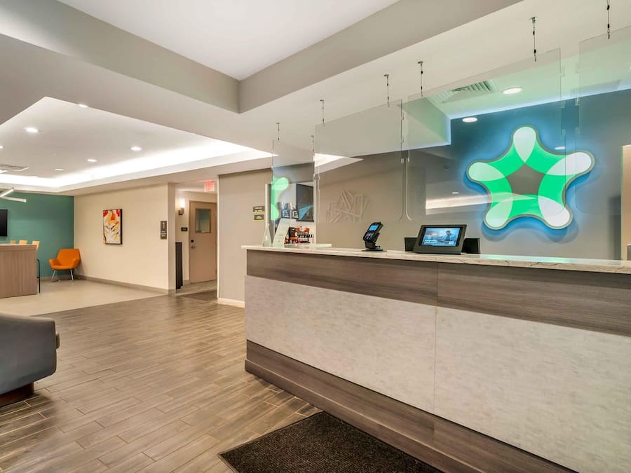 A modern reception area with a counter, seating, and a large screen.